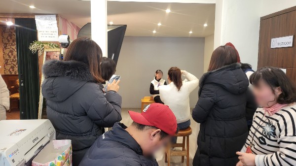 이용인들이 사진관에서 사진사의 부탁에 따라 포즈를 취하며 사진을 찍는 모습.jpg